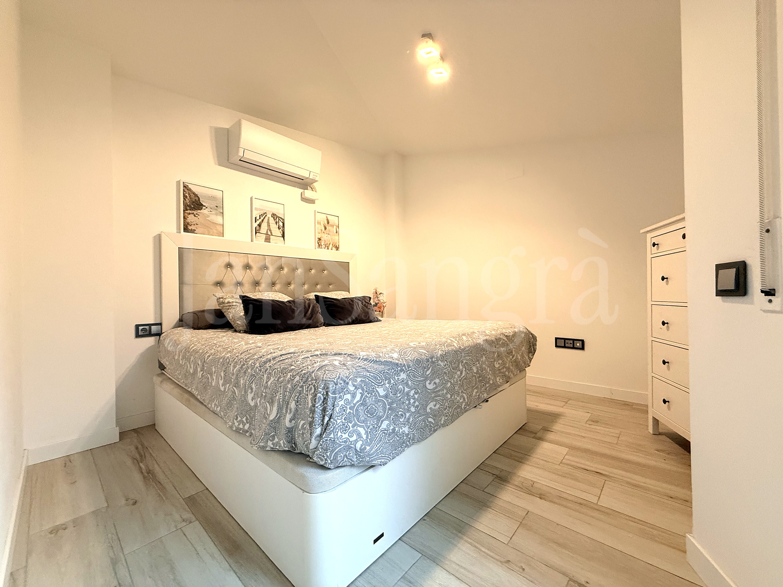 Dormitorio principal con cabezal tapizado y aire acondicionado