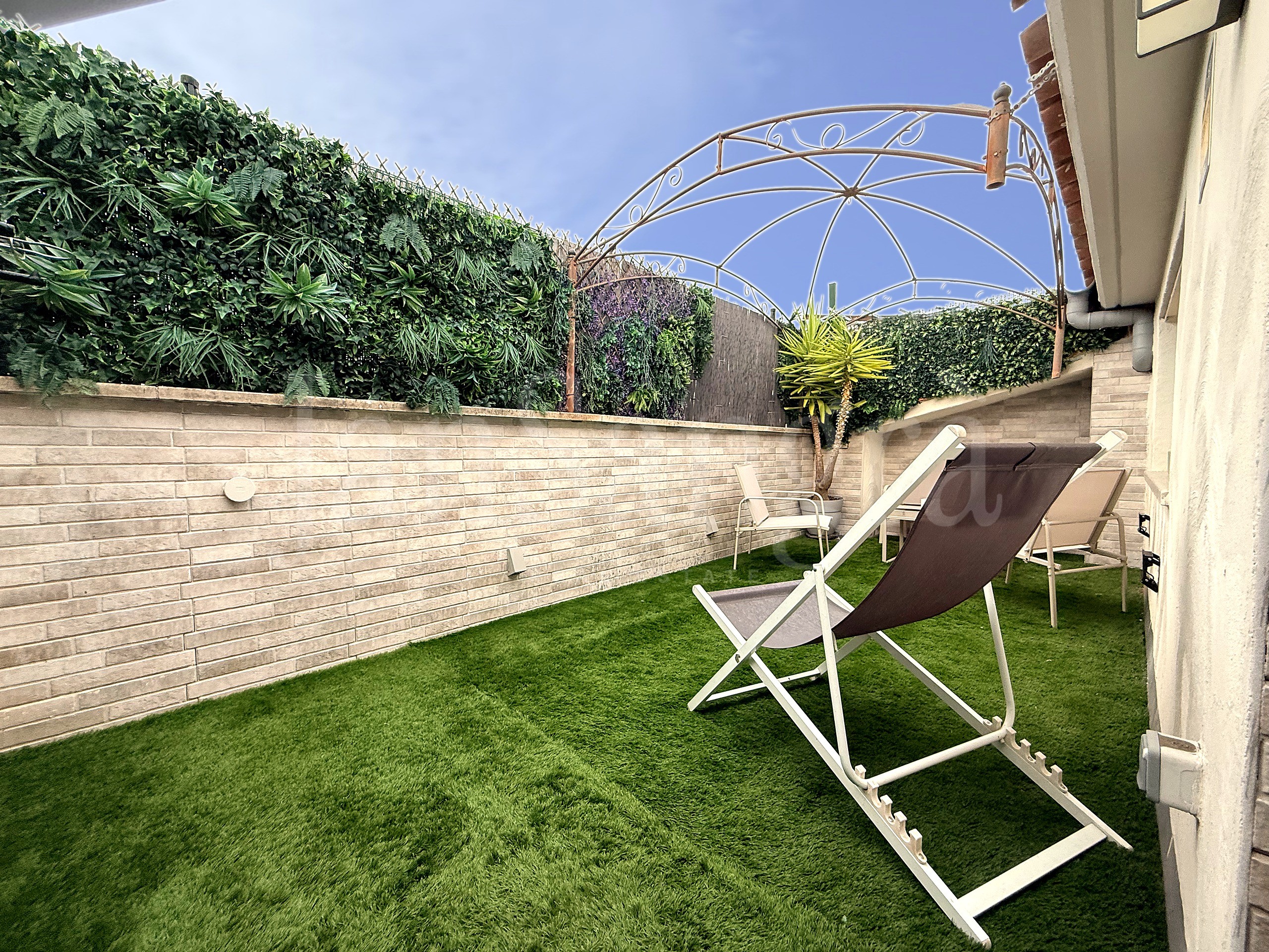 Terraza privada con césped artificial y pérgola